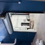 Open loading bay in a blue-walled industrial space with a mounted chain hoist and hanging chains visible outside the doorway.